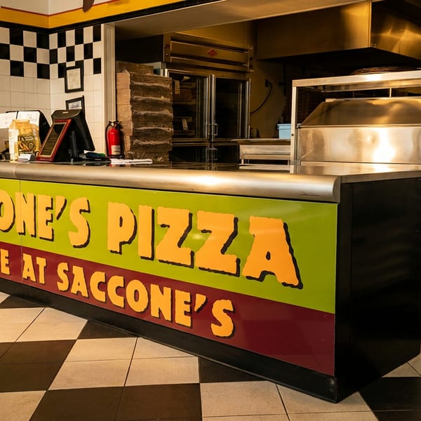 The interior of Saccone's Pizza, showing the counter with computers and kitchen equipment in the background.